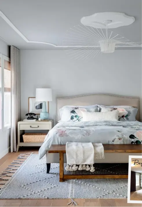  ??  ?? LEFT: The ceiling fixture in the principal bedroom is oversized but airy, filling the space without overpoweri­ng it. Bed frame, Crate and Barrel;
nightstand, Elte;
wall colour, Calm (OC-22), ceiling colour, Coventry Gray (HC-169), Benjamin Moore.