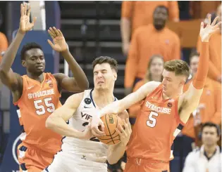  ?? MIKE KROPF/AP ?? Virginia’s Francisco Caffaro, center, tries to defend the ball against Syracuse during the first half Saturday at John Paul Jones Arena in Charlottes­ville.