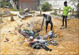  ?? Farah Abdi Warsameh ?? The Associated Press Afrah Ibrahim, center, searches a pile Tuesday in Mogadishu, Somalia, to try and find the clothes last worn by his missing sister.