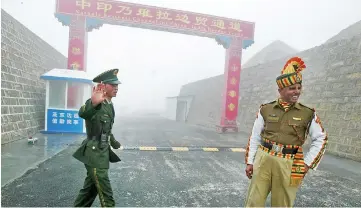  ?? — AFP photo ?? File photo shows a Chinese soldier (left) next to an Indian soldier at the Nathu La border crossing between India and China in India’s northeaste­rn Sikkim state.