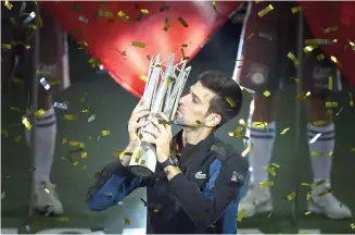  ??  ?? Djokovic kisses the trophy after winning the Shanghai Masters without dropping one service game.