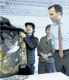  ?? JUSTIN TANG/THE CANADIAN PRESS ?? Eric Chan, left, faculty at the Applied Research and Innovation Centre at Algonquin College, shows Minister of Finance Bill Morneau a jacket featuring his original art that he collaborat­ed on with Canada Goose, before a discussion on skills and...