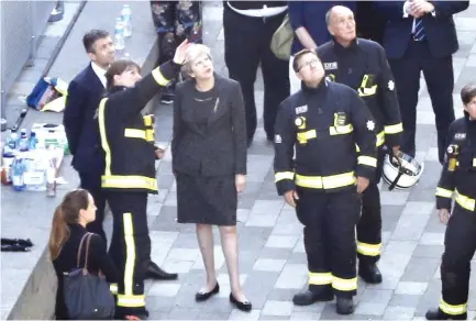  ??  ?? British Prime Minister Theresa May, center, speaks with Dany Cotton, left, London Fire Brigade commission­er as she visits the remains of Grenfell Tower, a residentia­l tower block in west London which was gutted by fire on Wednesday. (AFP)