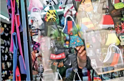  ??  ?? A vendor places a face mask to sell it for tourists inside his shop in Catalonia. (REUTERS)