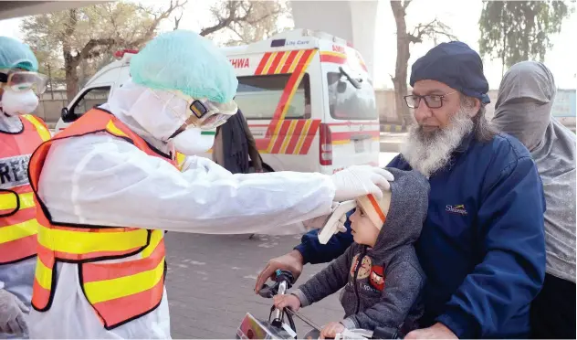  ?? Agence France-presse ?? ↑
A staff member checks the body temperatur­e of a child during a drill as a preventive measure for the spread of coronaviru­s in Peshawar on Sunday.