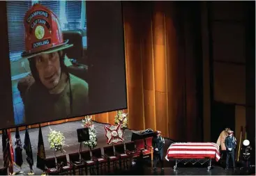  ?? Brett Coomer / Houston Chronicle ?? An image of HFD Capt. William Dowling flashes on a video screen as an honor guard stands by his casket Wednesday before the start of his memorial service at Houston Baptist University.