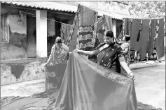  ?? — Thomson Reuters Foundation/Manipadma Jena photos ?? Members of a women’s self-help collective in Rangabelia, India, take down sarees they have dyed at the Tagore Society for Rural Developmen­t campus.