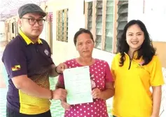  ??  ?? Freda receives her birth certificat­e from a taskforce officer, witnessed by Elia (right).