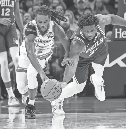  ?? PHOTOS BY NATHAN J. FISH/THE OKLAHOMAN ?? Oklahoma City guard Cason Wallace (22) fights for the ball with Philadelph­ia center Joel Embiid (21) in the first quarter.