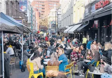  ?? ALBERTO PEZZALI/AP ?? Crowds of people gather at cafes and pubs Monday in London’s Soho district on the day some of England’s virus lockdown restrictio­ns were eased.