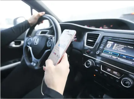  ?? JIM WELLS ?? A Calgary driver checks her phone while behind the wheel on Saturday. Police say courts are getting tougher on distracted drivers.