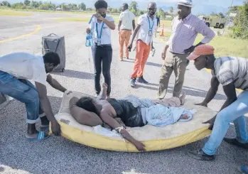  ?? JOSEPH ODELYN/AP ?? A mattress is used to transfer an injured quake survivor by plane from Les Cayes to Port-au-Prince, Haiti.