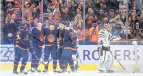  ?? JASON FRANSON/AP ?? Blackhawks goalie Kevin Lankinen, right, looks on as the Oilers celebrate a goal during the first period on Saturday.