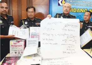  ?? BERNAMAPIX ?? Mohd Roslan (centre) showing a pyramid scheme chart seized in the raid.