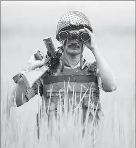  ?? AP/CHANNI ANAND ?? An Indian Border Security Force soldier looks at the Pakistan side of the border through binoculars Saturday at Ranbir Singh Pura, India.