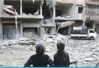  ??  ?? ARBIN: Syrian children look at a building that was damaged in a missile attack on the rebel-held besieged town of Arbin, in the eastern Ghouta region on the outskirts of the capital. —AFP