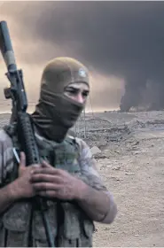  ??  ?? An Iraqi soldier as smoke rises south of Mosul