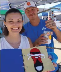  ?? Staff photo by Neil Abeles ?? ■ Becky Pickard shows the quiet books she makes by hand to teach fine-motor skills. Her husband, Donnie, shows the owls she likes to make from tin cans. The two were part of Atlanta’s Local Makers Market recently.