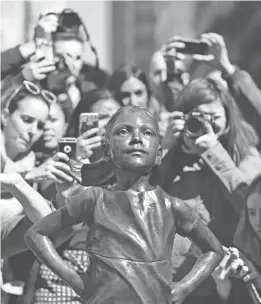  ?? ASSOCIATED PRESS ?? People photograph the “Fearless Girl” statue in New York. The statue, created by artist Kristen Visbal, was installed by investment firm State Street Global Advisors.