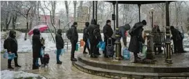  ?? EVGENIY MALOLETKA/AP ?? Ukrainians wait in line to collect water Thursday in Kyiv.“Strikes against civilian infrastruc­tures are war crimes,” French President Emmanuel Macron tweeted.