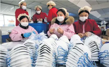  ??  ?? Workers producing facemasks at factory in Handan in China’s Hebei province; (inset) Royal Victoria Hospital