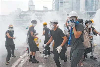  ?? Kin Cheung The Associated Press ?? Demonstrat­ors confront a cloud of tear gas Wednesday near the Legislativ­e Council in Hong Kong. Protesters had massed outside government headquarte­rs in opposition to an extraditio­n bill.