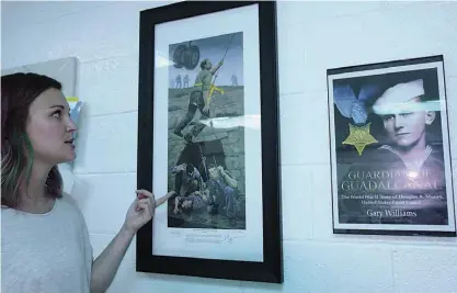  ??  ?? top
Whitney Farmer has a connection with the person shown kneeling in this Medal of Honor art display on her wall. During this summer’s teacher training at Valley Forge, Pa., she met the son of the man pictured, a soldier who received Medal of Honor.