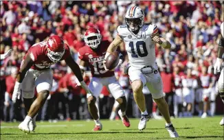  ?? MICHAEL WOODS/ASSOCIATED PRESS ?? Auburn quarterbac­k Bo Nix slips past Arkansas defenders Eric Gregory (left) and Simeon Blair as he runs for a touchdown during the second half Saturday in Fayettevil­le, Arkansas.