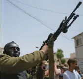  ?? NASSER NASSER/AP ?? A person wearing a mask shoots a gun Saturday during the funeral of a Palestinia­n man in the West Bank village of Azzun. Regional tensions have soared recently.