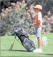  ??  ?? Matteo Velton tosses a golf ball in the air as he waits to tee off during a U.S. Kids Golf tournament.