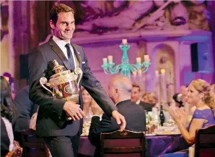  ??  ?? Roger Federer with his Wimbledon trophy at the Champions Dinner in London on Sunday. AFP