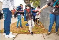  ?? JARROD VALLIERE U-T ?? Antonio Harris, a student at Perkins K-8 School in Barrio Logan, says goodbye to his father before heading to class with Ms. Bresee on Monday. The school had been closed for a year.