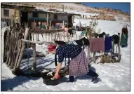  ?? ?? A woman puts out clothes to dry amidst the snow outside her home.