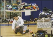  ?? AP PHOTO BY RICH PEDRONCELL­I ?? Mehdi Latrache tries on shoes at a donation center for victims of the recent wildfires Tuesday in Santa Rosa. Latrache and his family lost their Coffey Park home a week ago as a massive wildfire swept through the area.