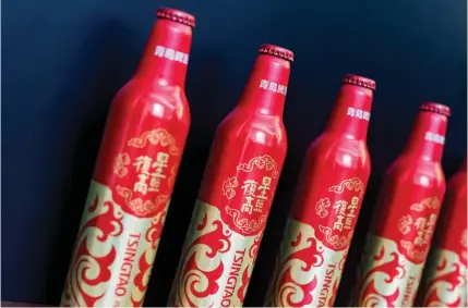  ?? BLOOMBERG ?? Bottles of Tsingtao Brewery beer customised to promote Fosun Internatio­nal are clearly differenti­ated from Tsingtao’s traditiona­l iconic green packaging