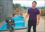  ?? WEN XINZHENG / CHINA DAILY ?? Tang Wei stands beside his boat, which he used to carry more than 300 people to safety during a flood last month in Nanping village, Ningxiang city, Hunan province.