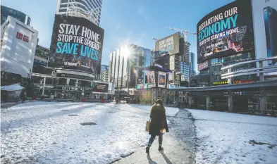  ?? PETER J. THOMPSON / FINANCIAL POST ?? A pedestrian walks through a largely empty Dundas Square in Toronto this week. A recent study has suggested that while commercial real estate in big cities has been affected by the pandemic, it should be far from being counted out.