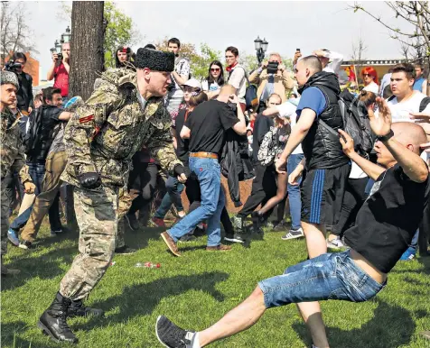  ??  ?? A National Liberation Movement member, left, pushes a protester down, during clashes at a demonstrat­ion against Vladimir Putin in Pushkin Square. Moscow, yesterday