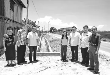  ??  ?? Foo (third left) and several MBKS officers pose near the completed concrete drain at Jalan Bintawa.