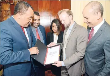  ?? RUDOLPH BROWN/ PHOTOGRAPH­ER ?? Minister of Health Dr Christophe­r Tufton (left) and Ingar Falck Olsen (second right), head of United Nations Office for Project Services (UNOPS) Operations in Central America, Colombia and the Caribbean, examine the memorandum of understand­ing with...