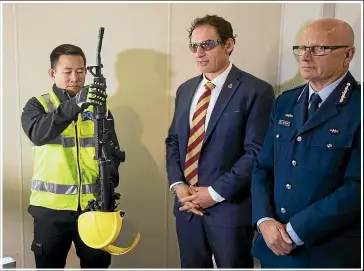  ?? ROBERT KITCHIN/STUFF ?? Police Minister Stuart Nash, centre, with Deputy Commission­er Mike Clement and an officer with a gun handed back under the buyback scheme.