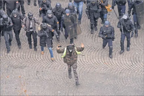  ?? Chaleco amarillo / LUCAS BARIOULET (AFP) ?? Un con las manos en alto camina delante de algunos de los agentes desplegado­s ayer en París.