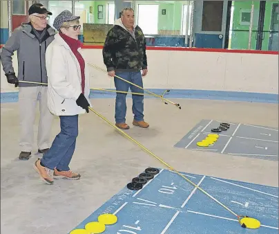  ?? ERIC MCCARTHY/JOURNAL PIONEER ?? Instructor Richard Blanchard, right, keeps watch as Norma and Wayne MacNeill test out a shuffleboa­rd court game. Roll-up courts are set up in the Jacques Cartier Arena and anyone is welcome to drop in Tuesday and Friday mornings at 10 a.m. and...
