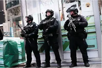  ?? PHOTO AFP ?? Des policiers lourdement armés surveillai­ent Times Square hier, un jour après l’attaque survenue dans le métro en pleine heure de pointe, qui a fait trois blessés.