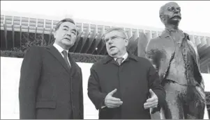  ?? PENG DAWEI / FOR CHINA DAILY ?? IOC President Thomas Bach introduces the Olympic Museum to Foreign Minister Wang Yi in Lausanne, Switzerlan­d, on Sunday, beside a statue of Pierre de Coubertin, founder of the modern Olympics.