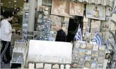  ?? — Reuters ?? A shop owner stands outside his souvenir shop in Athens.