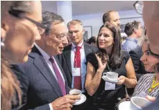  ?? FOTO: CHRISTIAN FLEMMING ?? Nach der Eröffnung nimmt sich EZB-Präsident Mario Draghi noch Zeit für eine Tasse Kaffee und antwortet auf Fragen von Nachwuchsö­konomen und Journalist­en.