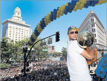  ?? PHOTOS BY RAY CHAVEZ — STAFF PHOTOGRAPH­ER ?? The Golden State Warriors’ Stephen Curry holds the Larry O’Brien NBA Championsh­ip Trophy as he rides on a double-decker bus during the Warriors championsh­ip parade in downtown Oakland on Tuesday.