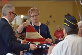  ?? MARIAN DENNIS — MEDIANEWS GROUP ?? Brian Parkes, executive director of the TriCounty Active Adult Center, and Kristine Parkes, regent for the Mahantawny Chapter DAR, assist with folding a flag during the ceremony.