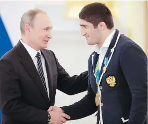  ?? — THE ASSOCIATED PRESS FILES ?? President Vladimir Putin shakes hands with wrestling gold medallist Abdulrashi­d Sadulaev, who received $93,000 and a racehorse as a reward.